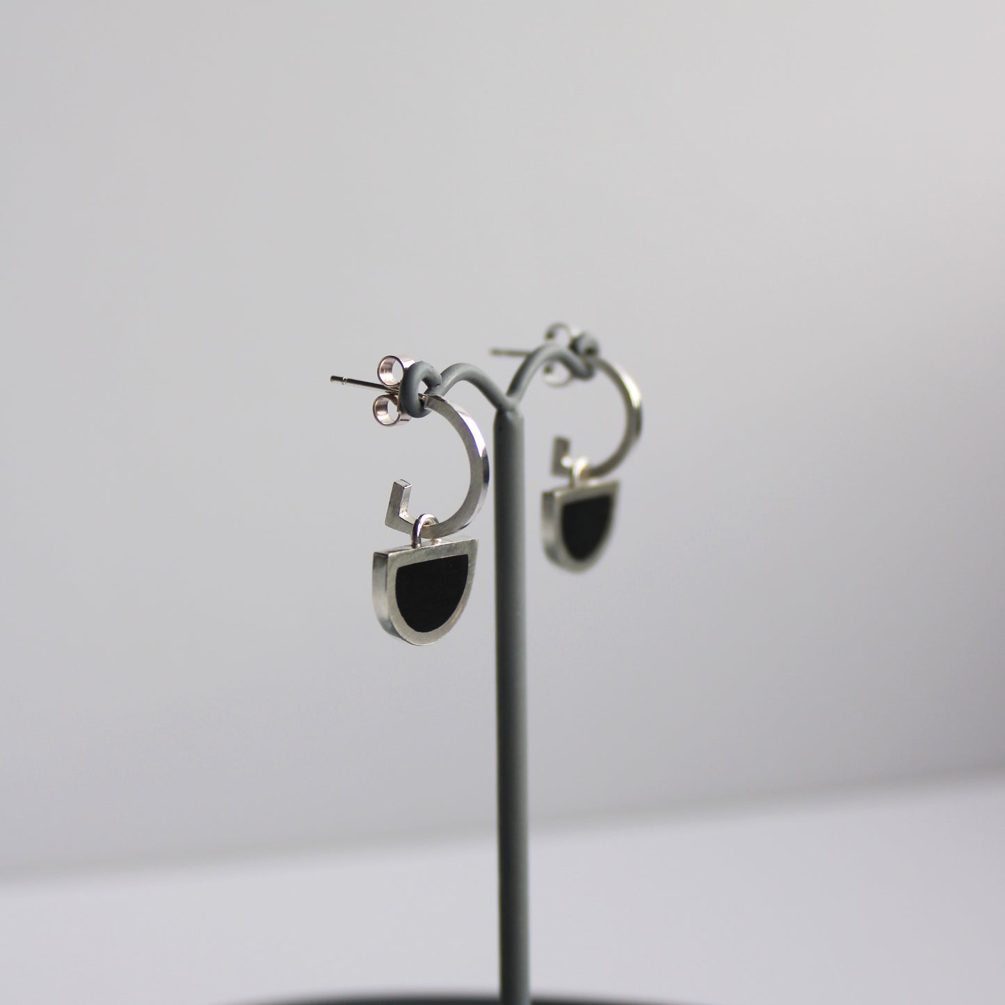 black resin and silver arc hoops on earring stand