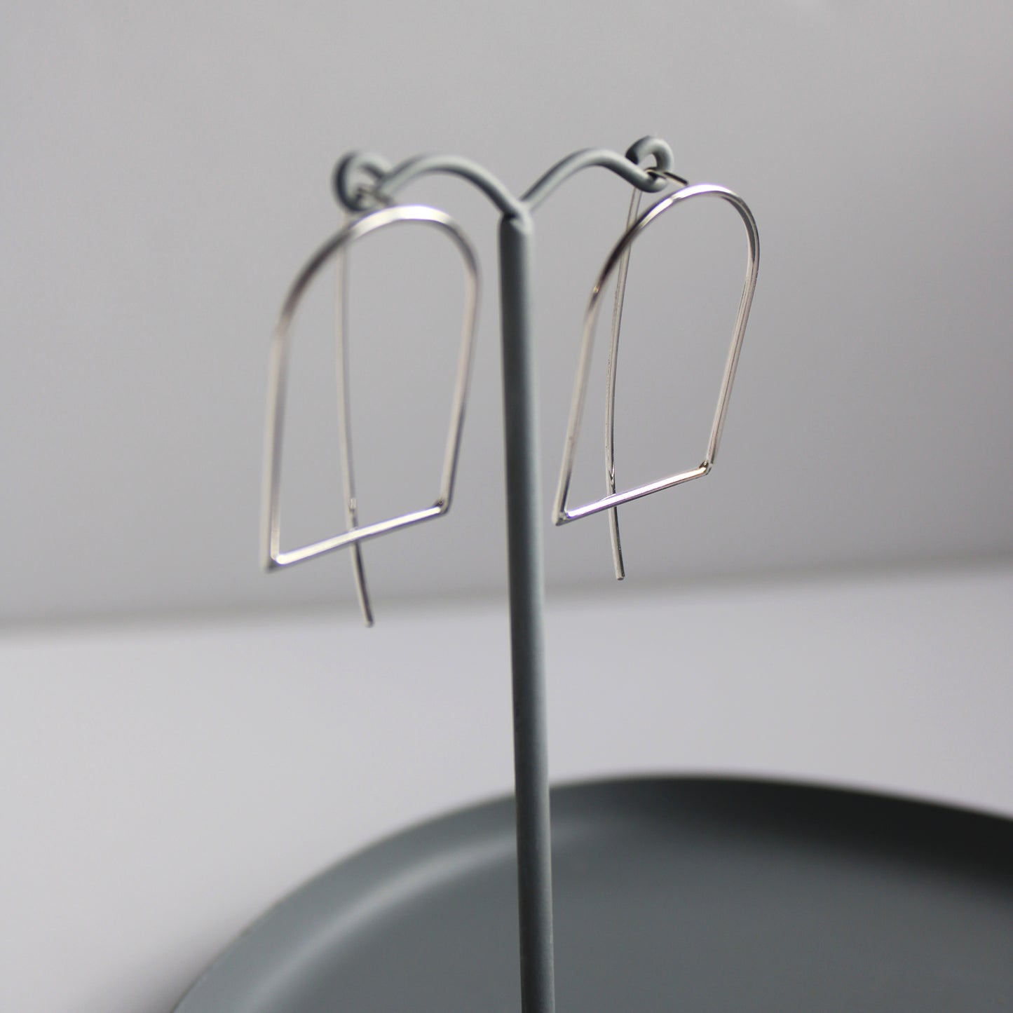 arc threader earrings on grey earring stand