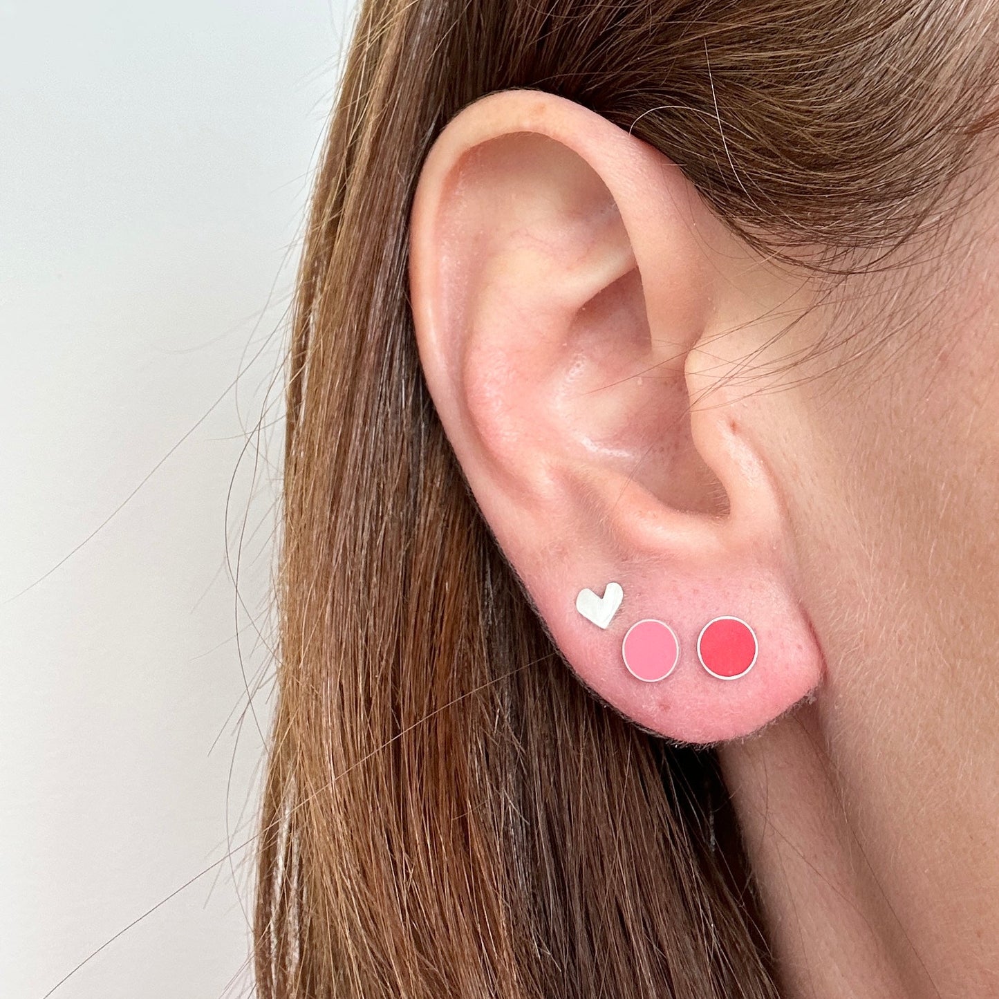 pink and red stud earrings worn