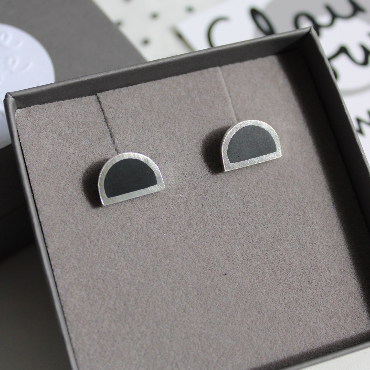 black and silver arc stud earrings in a box