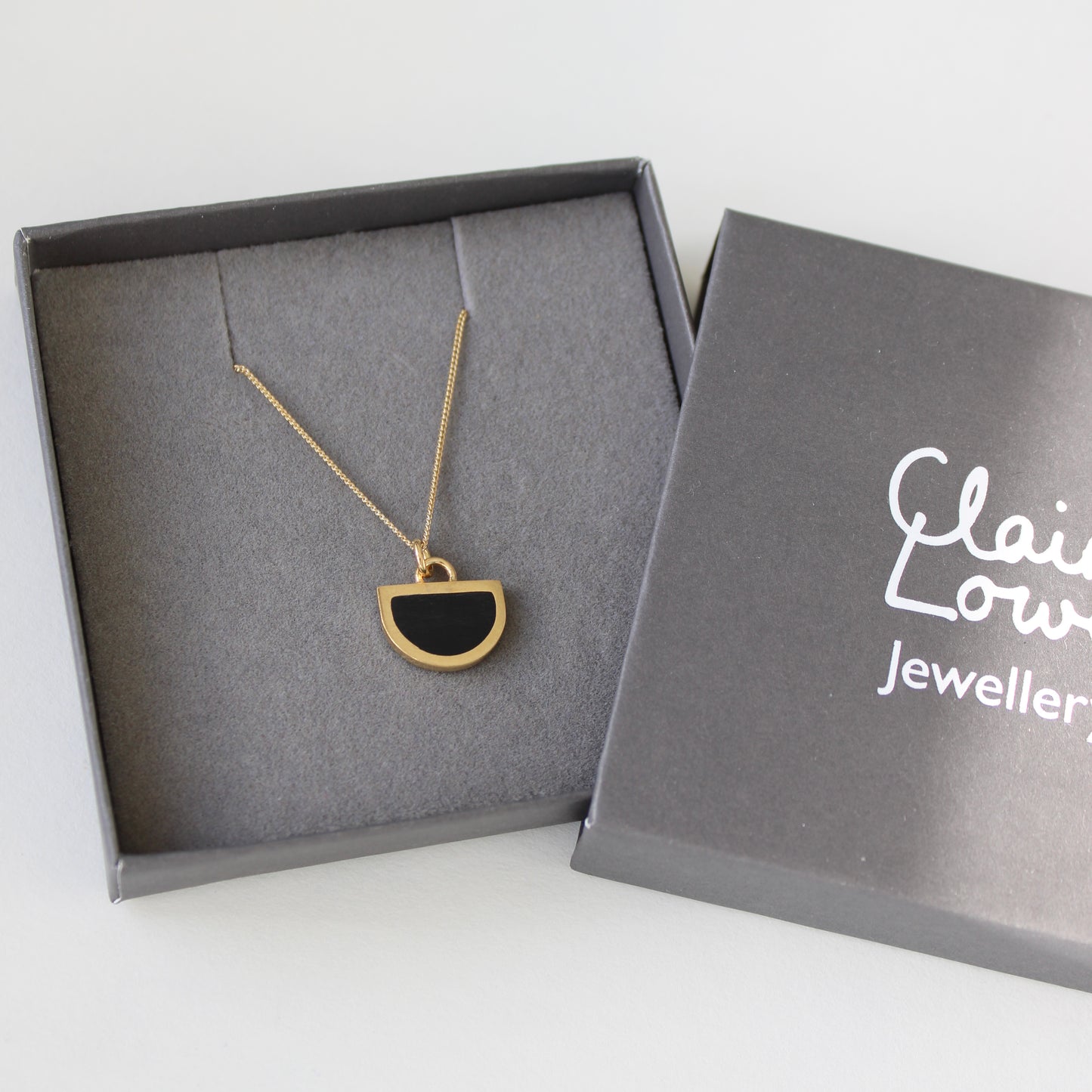 tiny black and gold arc pendant in box
