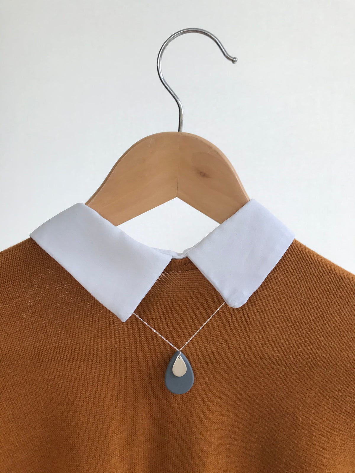 grey pebble pendant hung on a shirt on a coat hanger