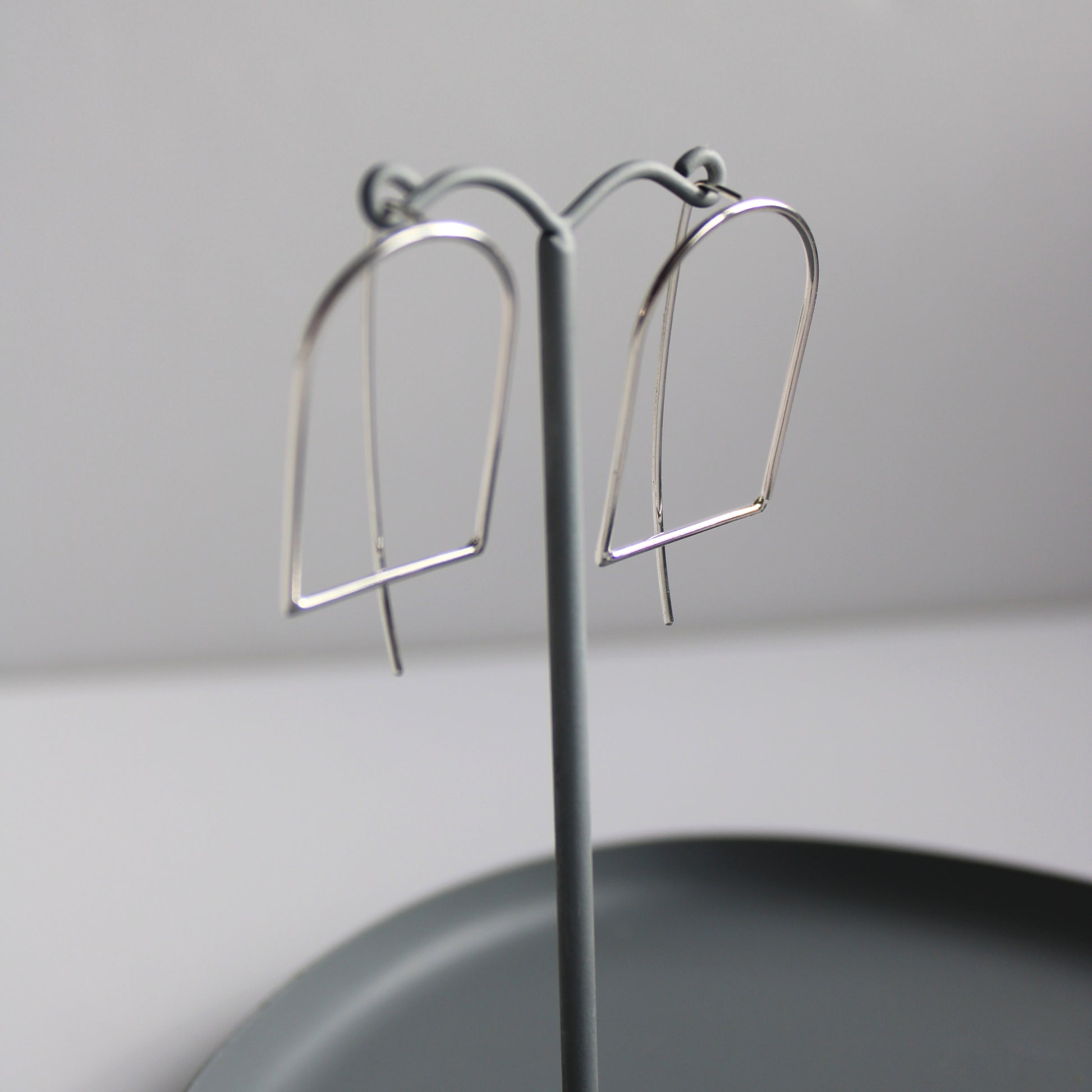 arc threader earrings on grey earring stand