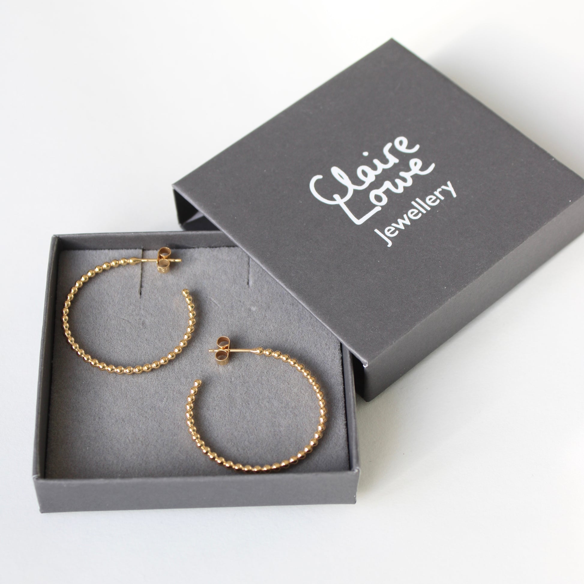 large dotty gold hoops in grey logo box