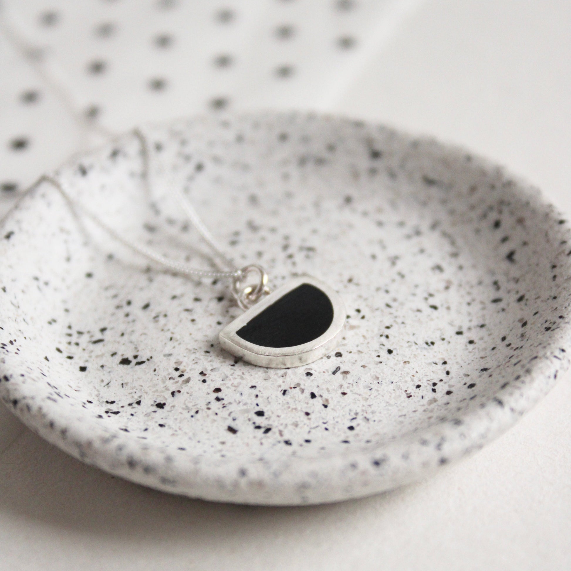 tiny arc black pendant on dish