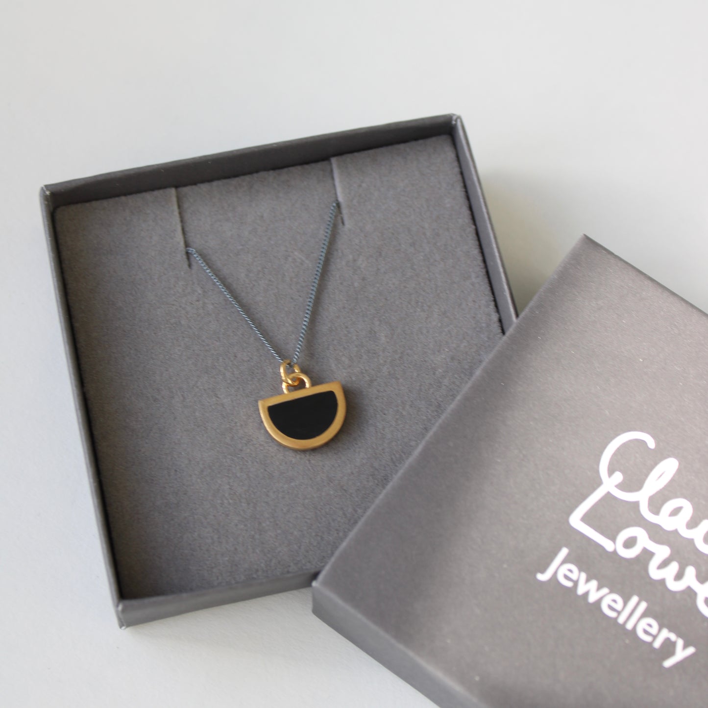 tiny black and gold arc pendant on oxidised silver chain in logo gift box